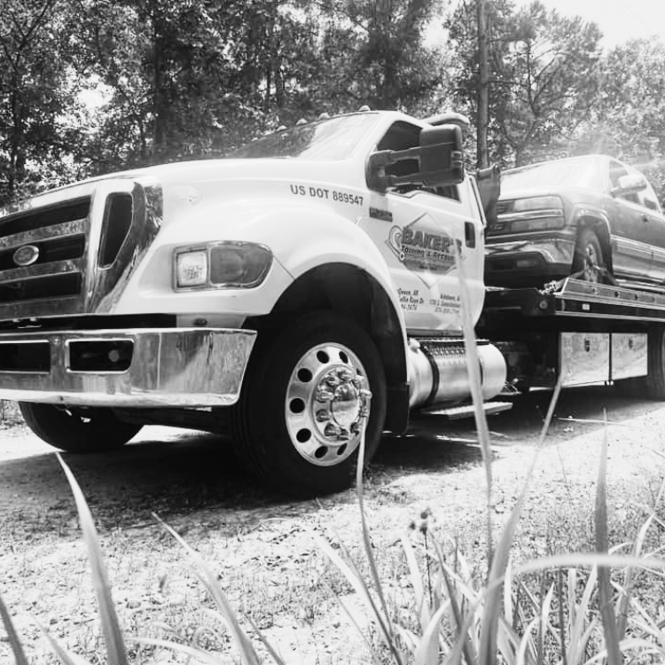 towing service De Queen AR flatbed tow truck transporting an SUV on gravel path