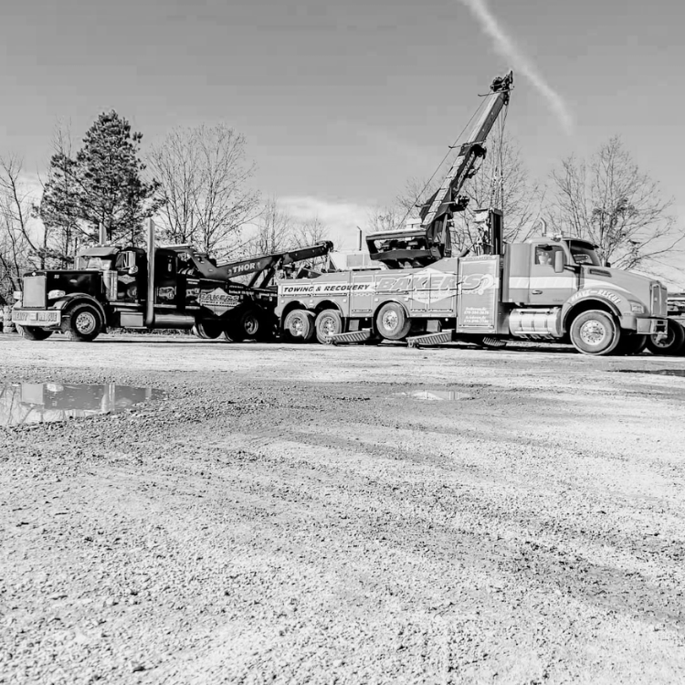 Two heavy-duty Baker's Towing & Recovery wrecker trucks parked back-to-back in staging lot