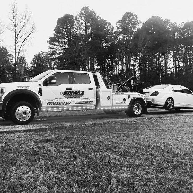 roadside assistance De Queen AR wrecker towing a luxury sedan on asphalt driveway