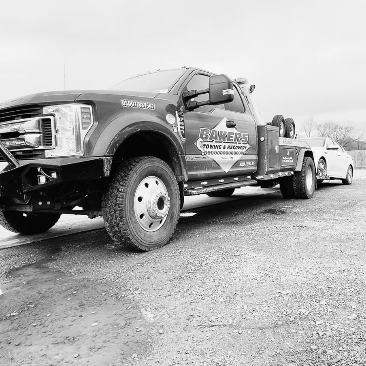 towing service Ashdown AR wrecker towing a sedan on gravel roadside